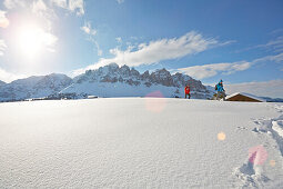 Group of people snow shoeing in front of a mountain hut, Kreuzwiesenalm, Luesen, South Tyrol, Italy