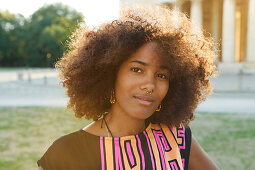 Portrait einer jungen afroamerikanischen Frau im Gegenlicht vor Sehenswürdigkeit, Königsplatz, München, Bayern, Deutschland