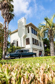 Ein alter schwarzer Cadillac vor einem typischen Florida Wohnhaus mit Palmen, Miami Beach, Miami, Florida, USA