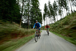 Zwei Fahrradfahrer fahren einen Weg herunter durch einen Wald