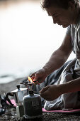 Junger Mann macht Kaffee mit einem Campingkocher, Freilassing, Bayern, Deutschland