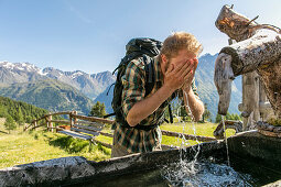Wanderer erfrischt sich das Gesicht mit Wasser an Quelle