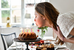 Mädchen pustet Kerzen auf Geburtstagskuchen bei Teenager Geburtstag von 14 jährigem Mädchen in Hamburg, Deutschland