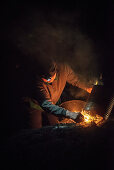 old charcoal burner woman lights kiln at night, charcoal production, Aalen, Baden-Wuerttemberg, Germany