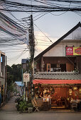 Thailänderin sitzt umgeben von zahlreichen Kabeln in einem menschenleeren Restaurant, Pai, Thailand, Südost Asien