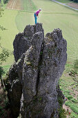 Junge Kletterin steht auf der Spitze eines hohen Felsens, Pottenstein, Franken, Deutschland