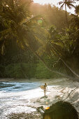 Junge Surferin geht am Strand entlang, Sao Tome, Sao Tome und Príncipe, Afrika
