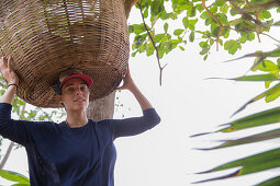 Junge Frau versucht einen großen Korb auf ihrem Kopf zu tragen, Sao Tome, Sao Tome und Príncipe, Afrika