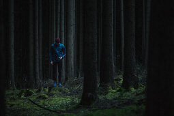 Junger Läufer steht im Wald und sieht nach unten, Allgäu, Bayern, Deutschland