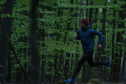 Young man running on a trail through a forest, Allgaeu, Bavaria, Germany