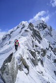 Woman back-country skiing ascending on rock- and iceridge to Care Alto, Care Alto, Adamello group, Lombardia, Italy