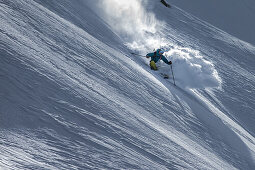 Young male skier riding through deep powder snow apart the slope, Andermatt, Uri, Switzerland