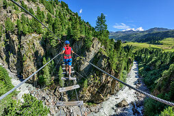 Woman crossing gorge on suspension bridge, Obergurgler Klettersteig, fixed-rope route, Obergurgl, Oetztal Alps, Tyrol, Austria