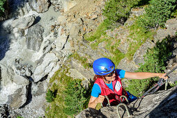 Woman climbing on Obergurgler Klettersteig, fixed-rope route, river in background, Obergurgler Klettersteig, Obergurgl, Oetztal Alps, Tyrol, Austria