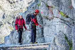 Man and woman climbing on fixed-rope route Sentiero dei Fiori, Sentiero dei Fiori, Adamello-Presanella Group, Trentino, Italy