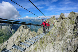Man and woman climbing on fixed-rope Sentiero dei Fiori over big .. Bridge, Sentiero dei Fiori, Adamello-Presanella Group, Trentino, Italy