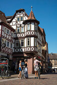 Paar mit Fahrrädern in Fußgängerzone der Altstadt mit Fachwerkhäusern, Lohr am Main, Spessart-Mainland, Bayern, Deutschland