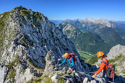 Two women climbing on fixed-rope route Mittenwalder Hoehenweg, Wetterstein range in background, fixed-rope route Mittenwalder Hoehenweg, Karwendel range, Upper Bavaria, Bavaria, Germany