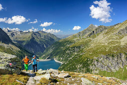 Man and woman hiking, barrier lake Zillergrund in background, hut Plauener Huette, Reichenspitze group, Zillertal Alps, Tyrol, Austria