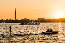 Boote und Wassersportler auf dem Wasser der Außenalster zum Sonnenuntergang, Hamburg, Deutschland