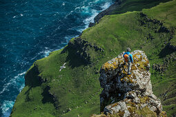 Man standing on the top of a rock in the mountains, Faeroe Islands