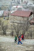 Drei Skifahrer laufen zu einem Dorf hinunter, Gudauri, Mzcheta-Mtianeti, Georgien