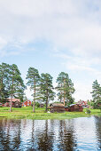 Sicht vom Wasser auf das Dorf Bodarna mit seinen roten Holzhäuser, Sollerön, Dalarna, Schweden
