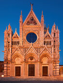 Fassade des Dom Cattedrale di Santa Maria Assunta in Siena mit der Pforte, rundem Glasfenster und Fresken in der blauen Stunde, Toskana, Italien