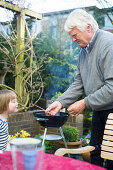 Granddaughter und grandfather blowing matches, Hamburg, Germany