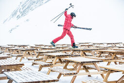 Young male skier walking over tables from a restaurant in the mountains, Kaprun, Salzburg, Austria