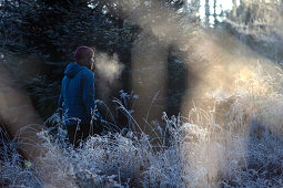 Young male runner standing in a frost covered forest, Allgaeu, Bavaria, Germany