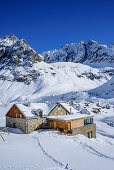 Woman backcountry skiing sitting at hut Winnebachseehuette, hut Winnebachseehuette, Stubai Alps, Tyrol, Austria
