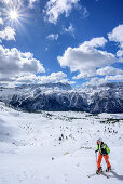 Woman backcountry skiing ascending towards Forca del Palone, Kanin group in background, Forca del Palone, Julian Alps, Friaul, Italy