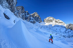 Woman backcountry skiing ascending towards Sella Nabois, Jof Fuart and Sella Nabois in background, Julian Alps, Friaul, Italy