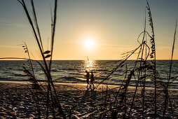 Ein Paar geht am Strand am Golf von Mexiko zum Sonnenuntergang spazieren, Boca Grande, Florida, USA