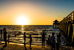 Sonnenuntergang am beliebten öffentlichen Strand am Naples Pier am Golf von Mexiko, Naples, Florida, USA