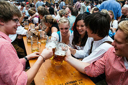 Feiernde stoßen mit ihren Bierkrügen an, Oktoberfest, München, Deutschland