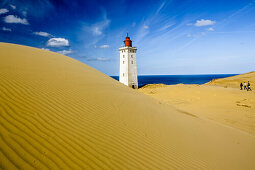 Tourists walking towards a lighthouse, Rubjerg Knude Fyr, Lokken, Jammerbucht, North Sea, Skagen, Denmark