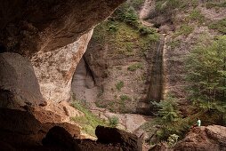 ' hiker sits inside the natural wonder called ''Ofenloch'', canton St. Gallen, Switzerland, Europe'