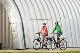 Man and woman on eBikes, City, Munich, Bavaria, Germany