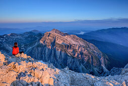 Woman hiking sitting at sunrise at Corno Grande, view to Gran Sasso-group, Corno Grande, Gran Sasso, Abruzzi, Italy