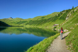 Woman hiking alongside lake Tappenkarsee towards Tappenkarseealm, lake Tappenkarsee, Radstadt Tauern, Salzburg, Austria