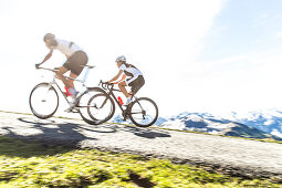 Zwei junge Menschen auf ihren Rennrädern in den Kitzbühler Alpen, Kitzbühlerhorn, Tirol, Österreich