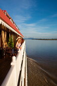 Young woman stands at railing of Ayeyarwady (Irrawaddy) river cruise ship Anawrahta (Heritage Line), near Kyunttaw, Kachin, Myanmar