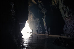 Zwei junge Männer laufen durch eine Höhle am Strand Praia da Amoreira,  Aljezur, Faro, Portugal