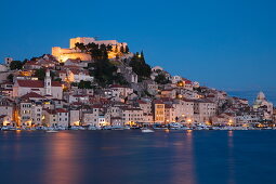 Beleuchtete Festung St. Michael und Häuser am Wasser in der Abenddämmerung, Šibenik, Šibenik-Knin, Kroatien, Europa