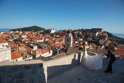 Asian wedding couple poses for wedding photos on city wall with view of Dubrovnik Old Town, Dubrovnik, Dubrovnik-Neretva, Croatia