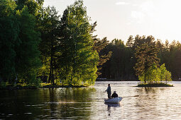 Angler im Ruderboot auf einem See mit kleinen Inseln , Schweden