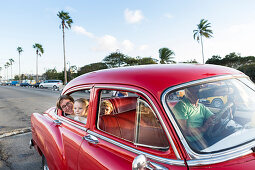 mother with children, sitting in a red oldtimer, comfortable seating, historic town center, old town, Habana Vieja, family travel to Cuba, parental leave, holiday, time-out, adventure, MR, Havana, Cuba, Caribbean island