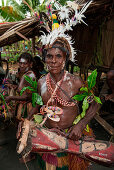 A man in traditional dress and headdress holds a drum and smiles during a cultural performance, Kopar, East Sepik, Papua New Guinea, South Pacific